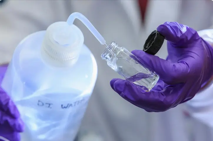 Chemik dodający wodę destylowaną do próbki. Źrodło: Canva.com
