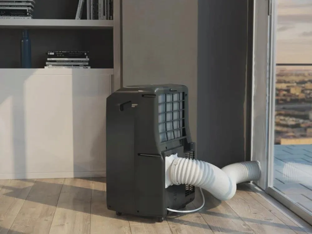 Klimatyzator przenośny Whirlpool PACF212HP B w salonie z podłączoną rurą wyrzutową.