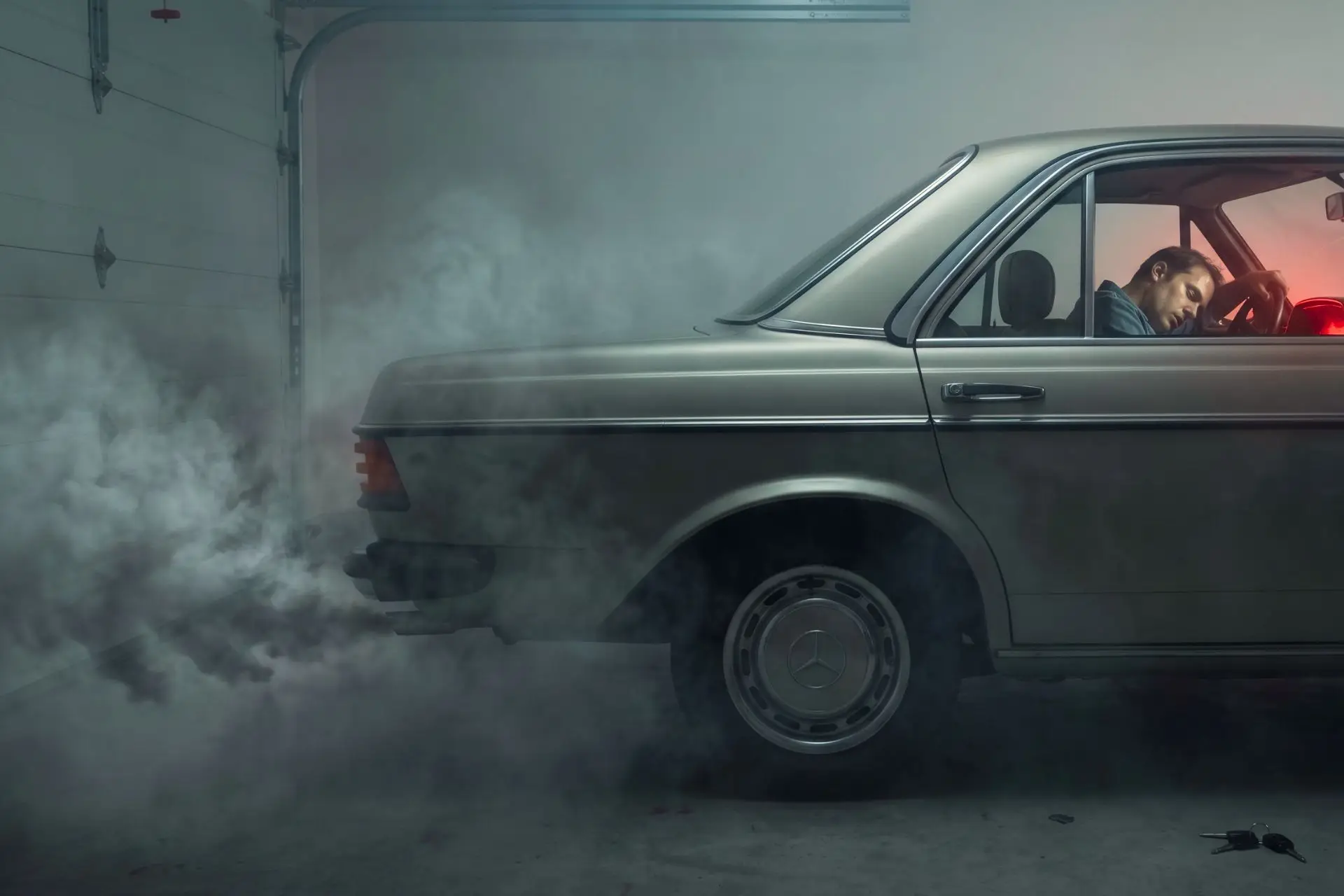 mężczyzna w aucie zaparkowanym w garażu i spaliny